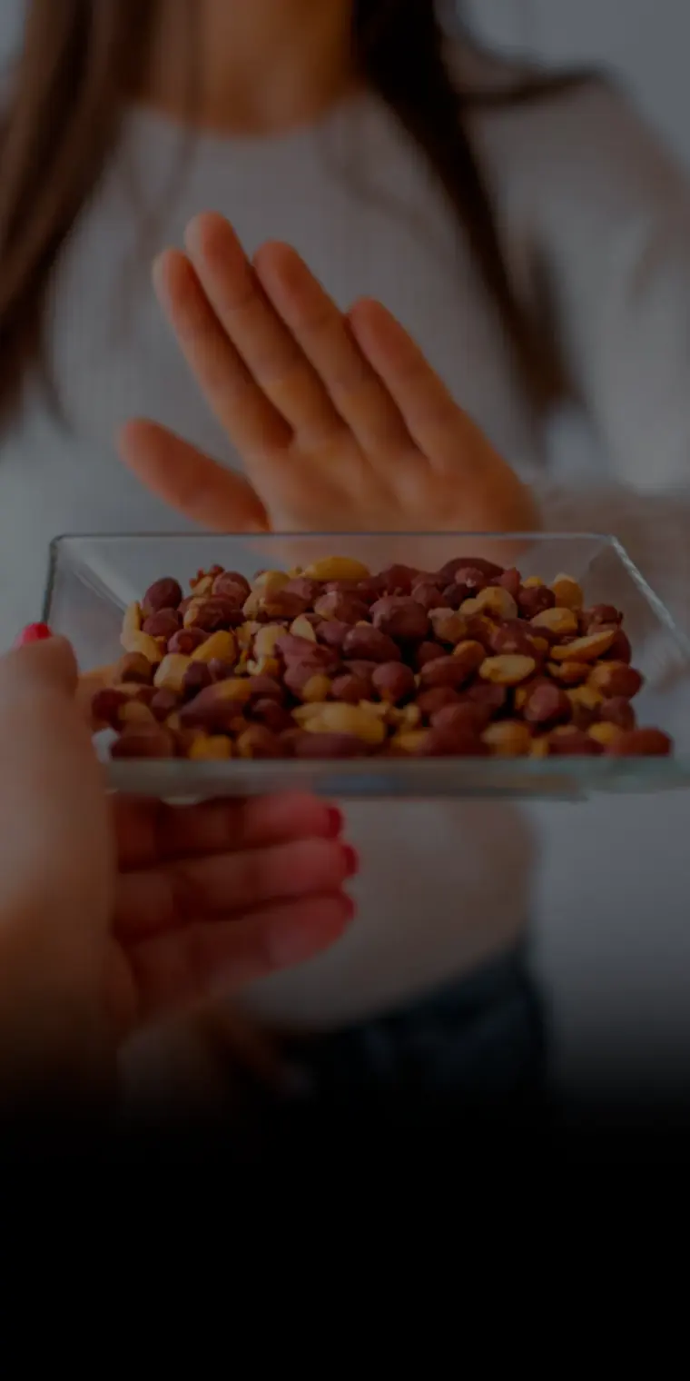 Pessoa recusando um prato de castanhas, alergia alimentar