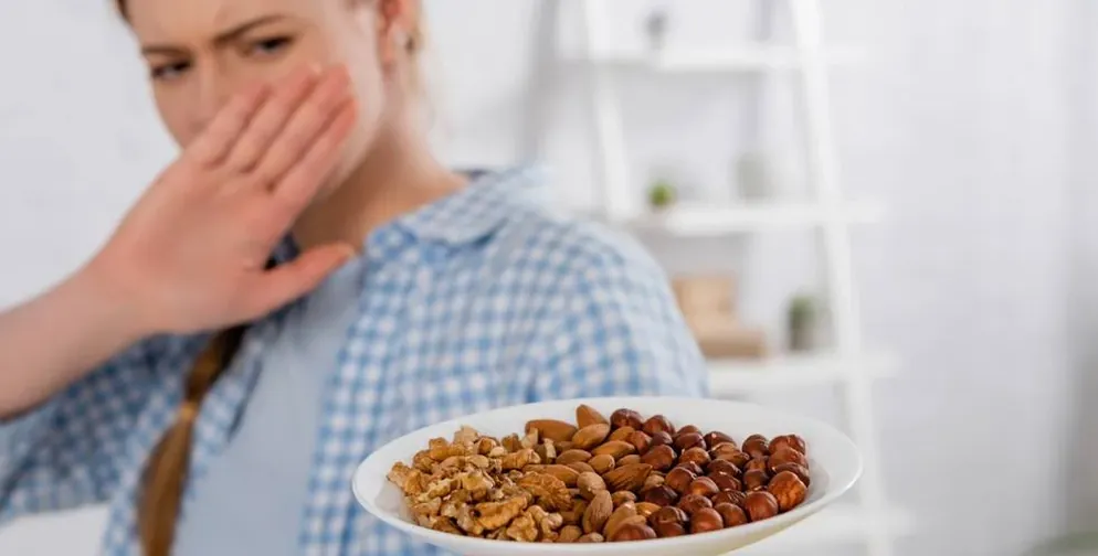 Pessoa recusando um prato de castanhas, alergia alimentar